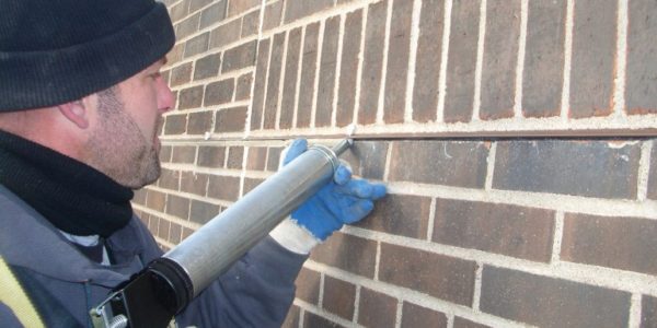 worker replacing sealant and caulking