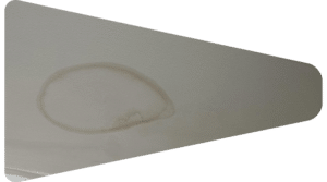 Circular brown water stain on an interior ceiling surface.